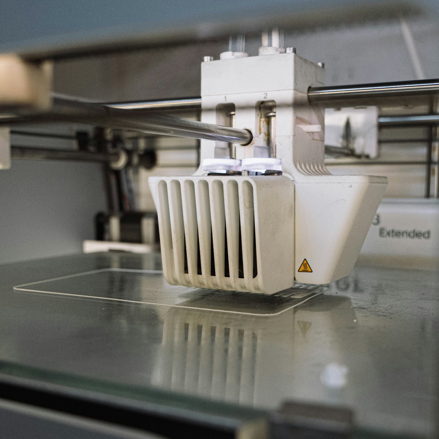 Głowica drukarki 3D układa przezroczysty filament na szkle.